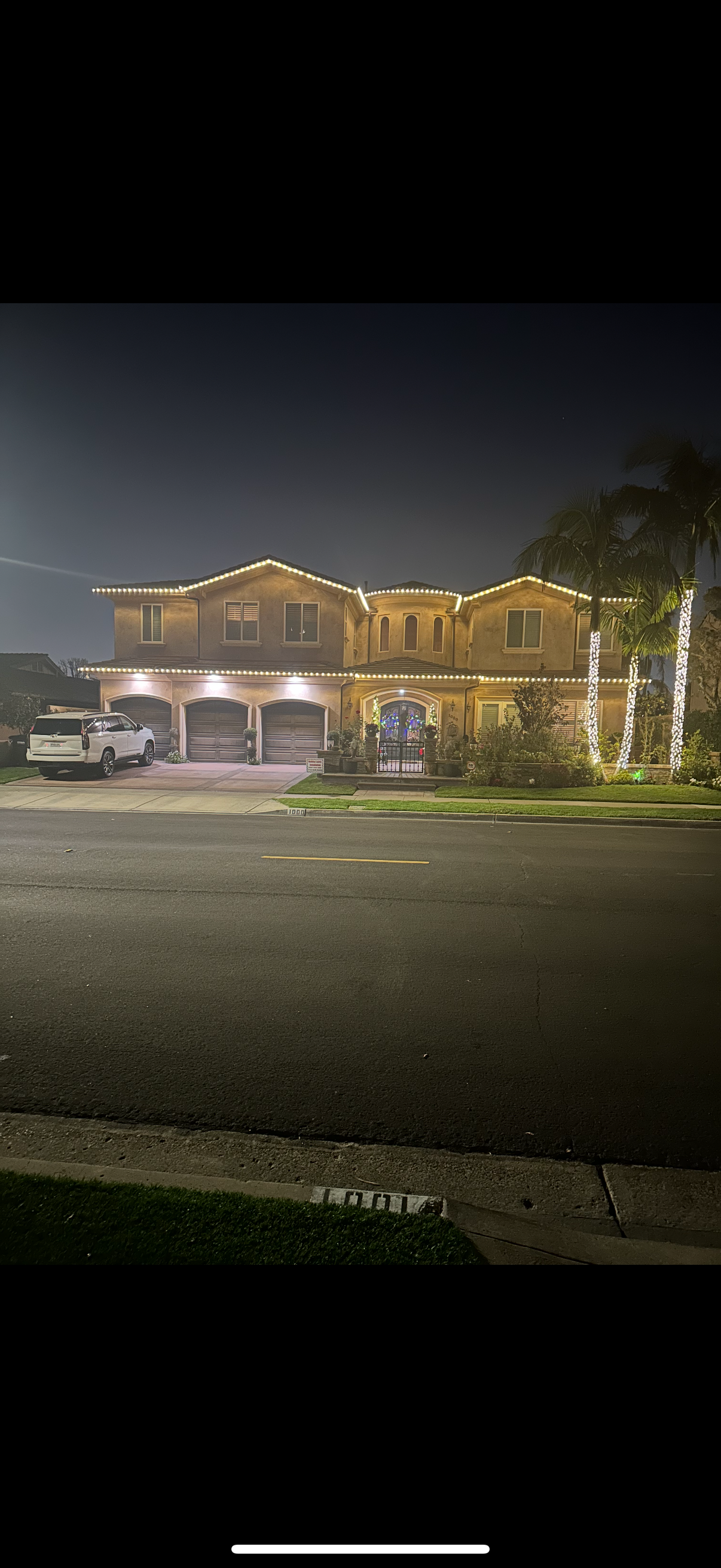 Large home with warm white roofline holiday lighting